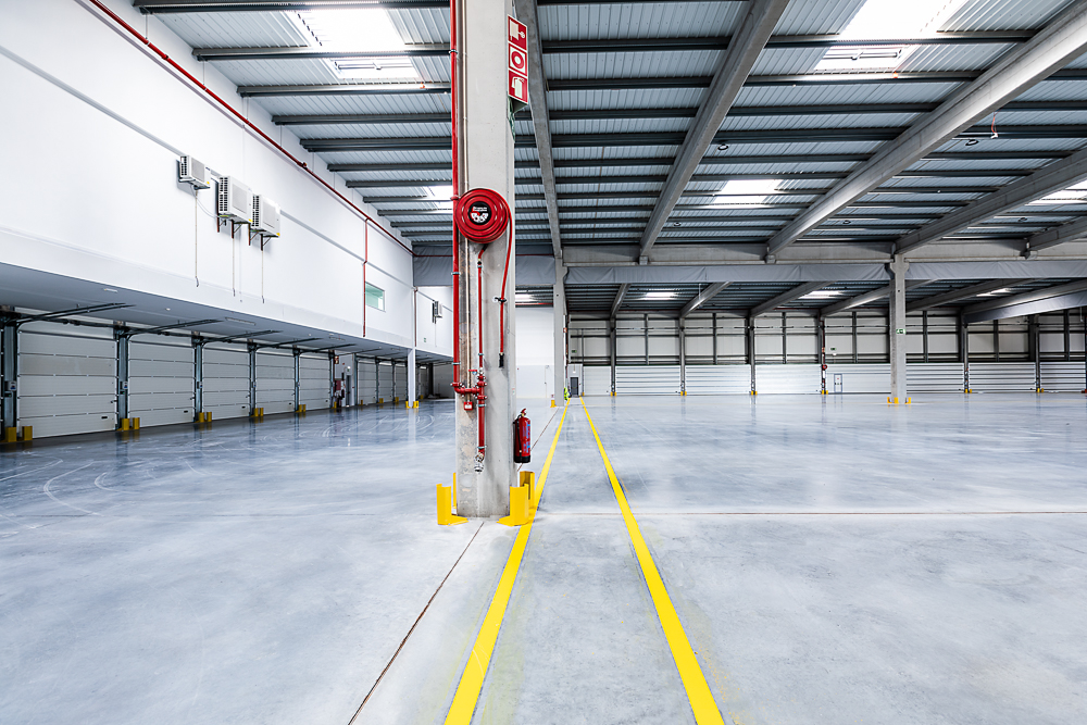 Parque Logístico - Sessão fotográfica num parque logístico, capturando a amplitude dos espaços industriais e a eficiência das instalações modernas. Com uma infraestrutura robusta e funcional, o cenário reflete a dinâmica e a precisão deste ambiente.